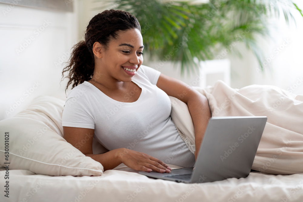 Online Work. Smiling Young Black Woman Using Laptop While Lying In Bed Online Work. Smiling Young Black Woman Using Laptop While Lying In Bed