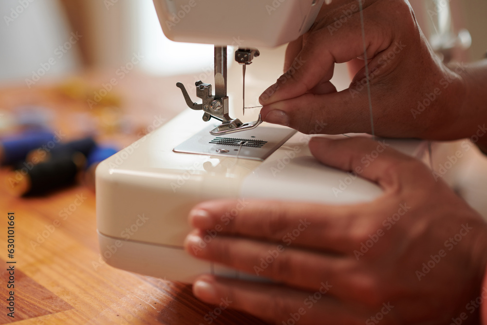Closeup image of seamstress threading sewing machine needle