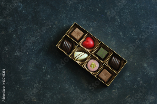 A set of beautiful sweets in a small box on a dark blue marble background. Overhead view, natural light. The concept of holidays, Valentine's Day
