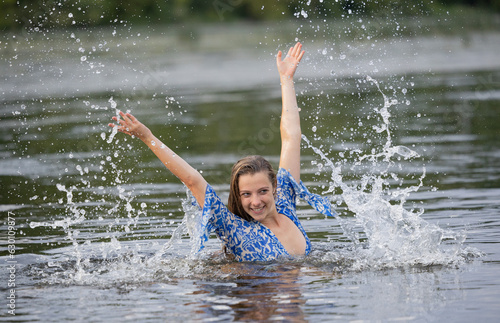 A young girl splashing in the river water on a hot summer evening