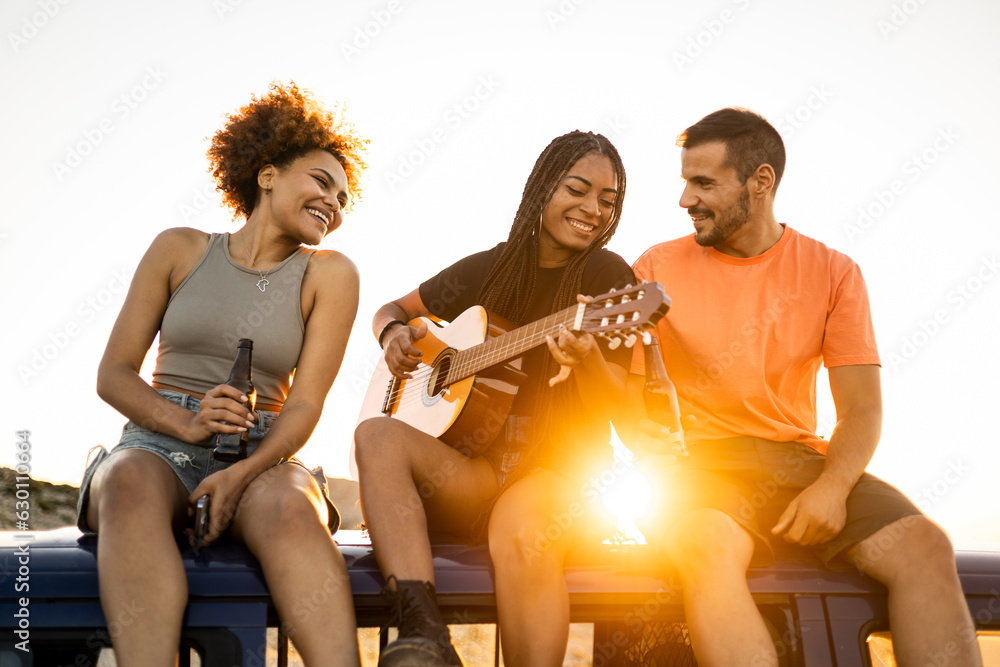 Φωτογραφία A group of 3 young people from all walks of life are having fun sitting on the roof of a camper van