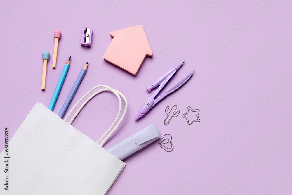 Composition with paper bag and different stationery on lilac background Composition with paper bag and different stationery on lilac background