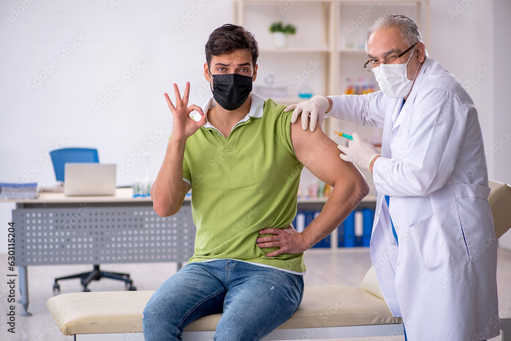 Fototapeta premium Young male patient visiting old male doctor in vaccination conce