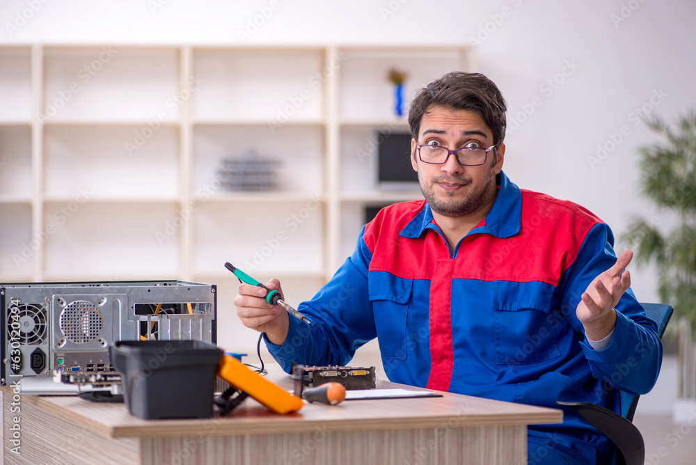 Young male repairman repairing computer Young male repairman repairing computer