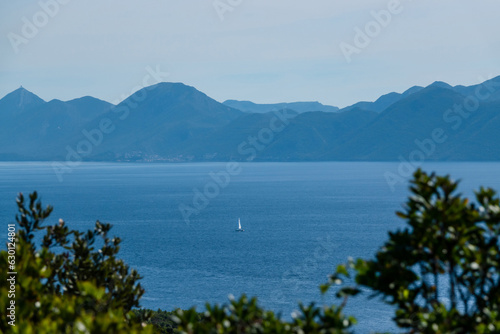 Beautiful view of a distant sailboat sailing peacefully on the blue Adriatic Sea