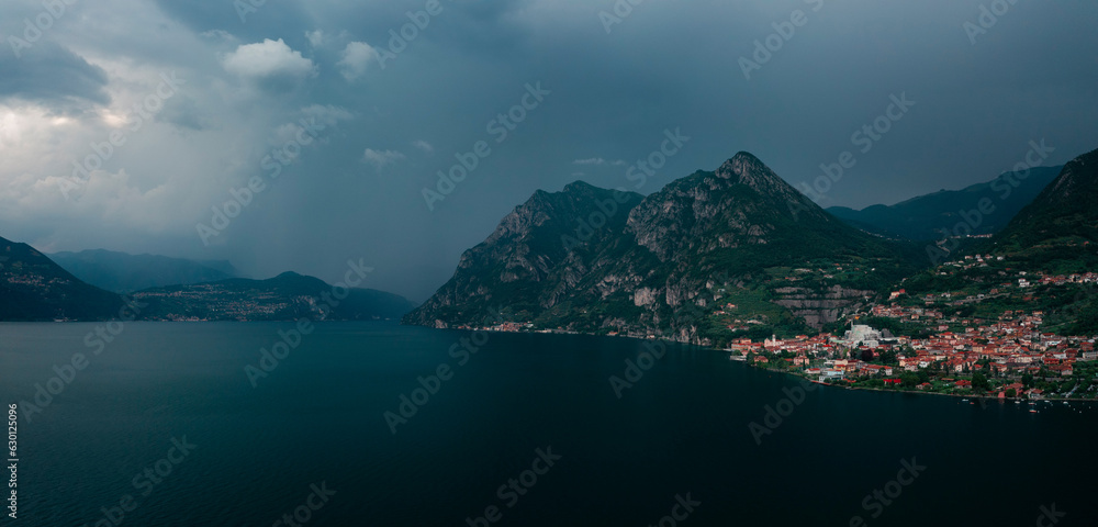 Mountain panorama at Lake Iseo with mountains and village Marone from above, during thunderstorm with dark sky and clouds, Italy