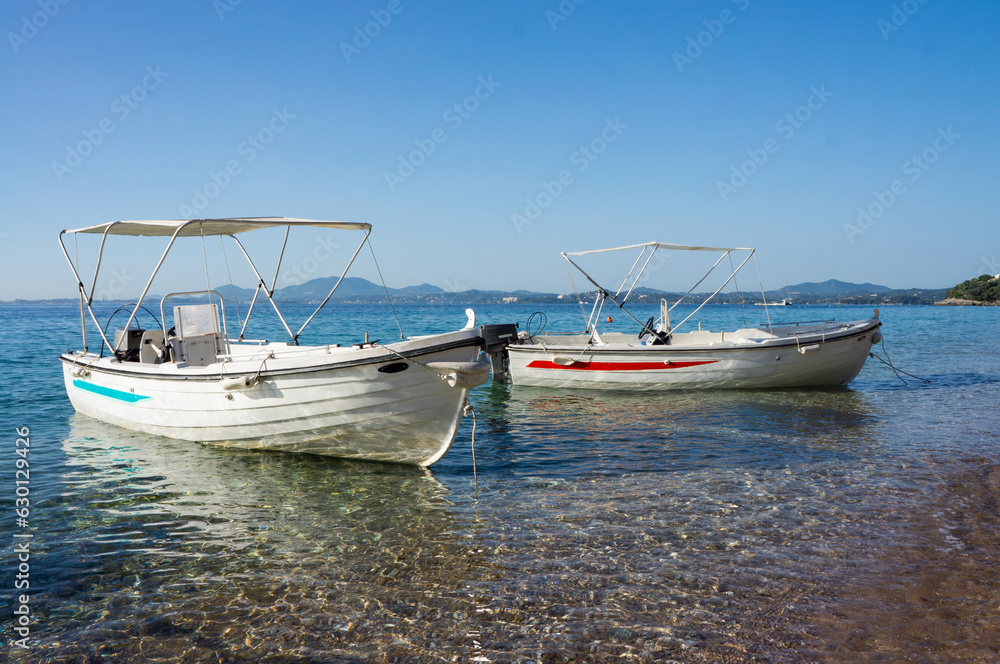 Two empty modern boats floating in beautiful blue sea on a sunny day. Mediterranean seacoast lonely beach. Two empty modern boats floating in beautiful blue sea on a sunny day. Mediterranean seacoast lonely beach.