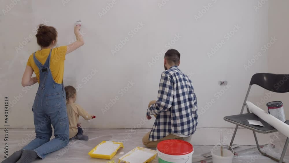 Friendly family mum dad and kid are painting wall and having fun during house renovation. Redesign and improvement new home for family. slow motion Friendly family mum dad and kid are painting wall and having fun during house renovation. Redesign and improvement new home for family. slow motion