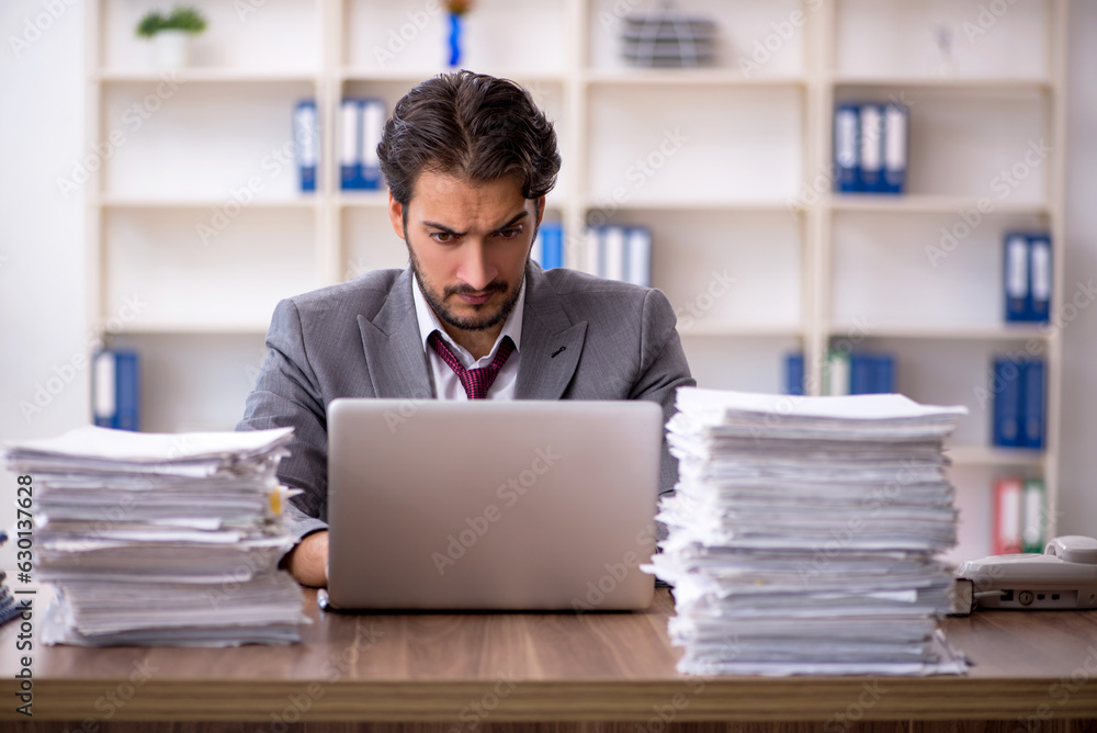 Young male employee and too much work in the office Young male employee and too much work in the office