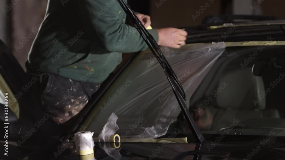Bodywork masking, Sanding car, Protect surfaces. Technician making sure to mask sanded car with tape before painting it. Bodywork masking, Sanding car, Protect surfaces. Technician making sure to mask sanded car with tape before painting it.
