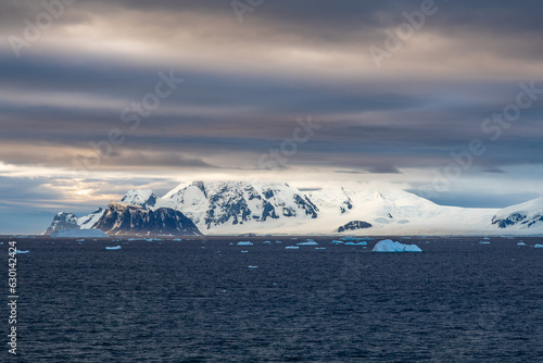 Evening Descends at Sunset on Pourquoi Pas Island, Antarctica Peninsula with Dark Cloudy Skies, Mountains, Snow and Icebergs © Jill Clardy