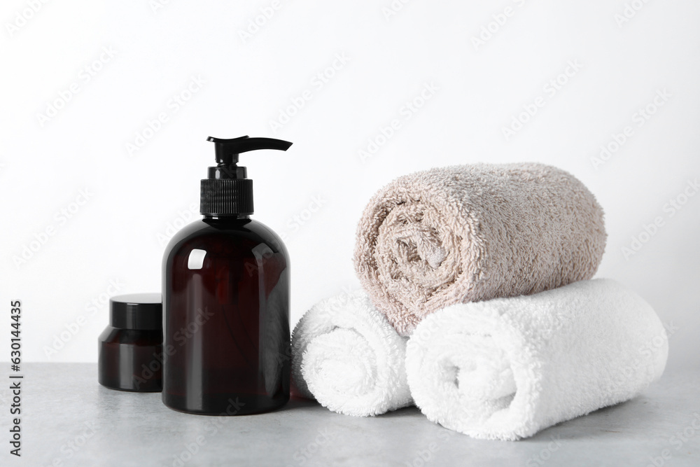 Cosmetic products and towels on light grey table Cosmetic products and towels on light grey table