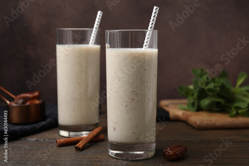 Glasses of delicious date smoothie, dried fruit and cinnamon on wooden table