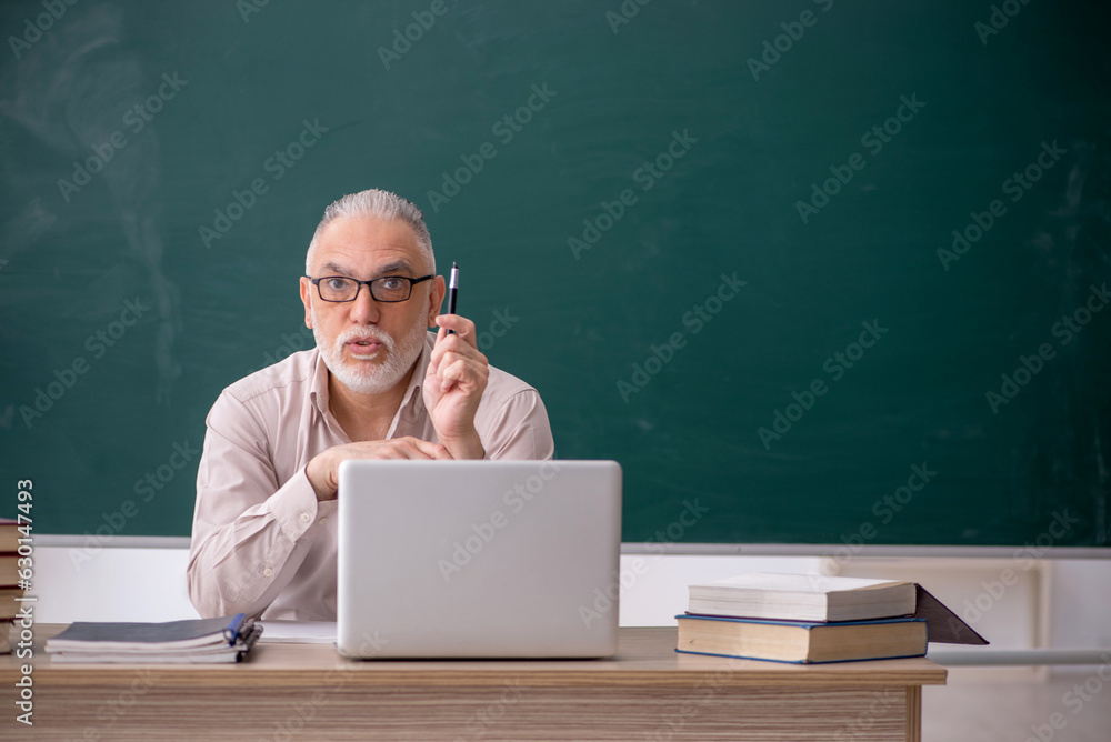 Old male teacher sitting in the classroom Old male teacher sitting in the classroom