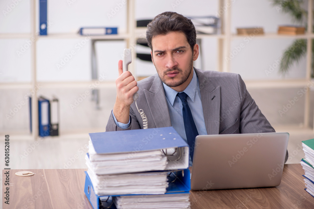Naklejka premium Young male employee and too much work in the office