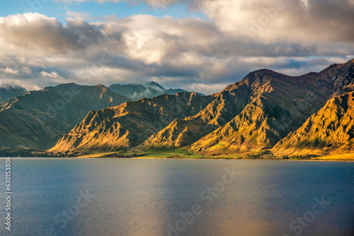 Rugged tall mountain range and lake side scenery around the shores of alpine Lake Hawea