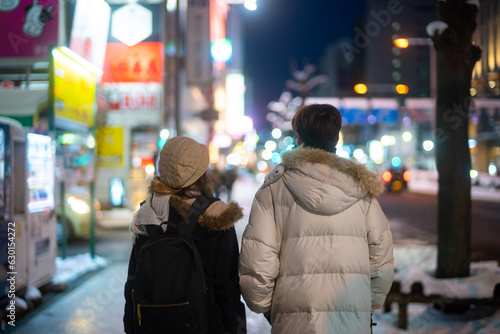 Asian couple dating and shopping at retail store street market together in the city at night. Man and woman enjoy and fun outdoor lifestyle nightlife walking city street in winter holiday vacation. © CandyRetriever 
