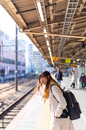 Young Asian woman in winter coat waiting for the trai in Japan. Attractive girl traveler enjoy outdoor lifestyle travel Japan by railroad transportation on winter holiday vacation.