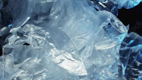 Vertical video. Plastic pollution. Ocean conservation. Waste disposal. Wet empty cellophane bags crushed bottles dump pile contamination on dark blue wrinkled texture background. photo
