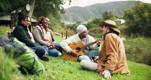 Fun, guitar and friends camping in nature with laughing, freedom and happy celebration at lake. Forest, outdoor adventure and singing to music, men and women on grass on summer weekend camp together. photo