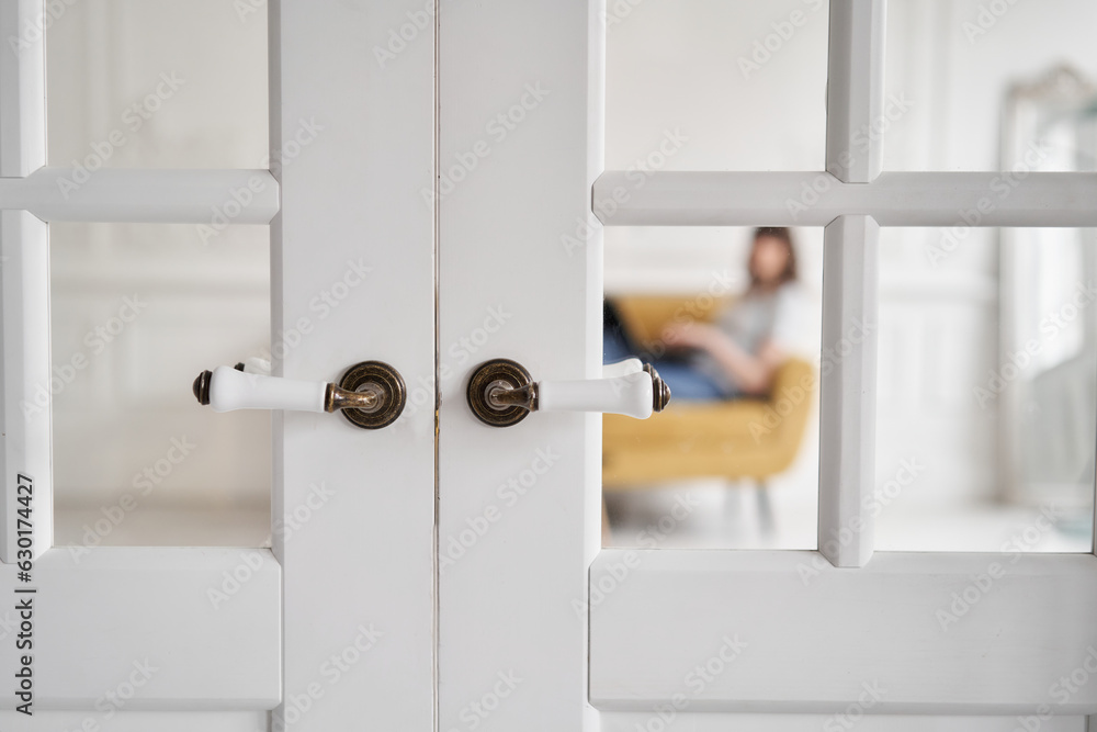 Old-style door, white - handle close up. The interior of a bright living room in a modern apartment. Old-style door, white - handle close up. The interior of a bright living room in a modern apartment.