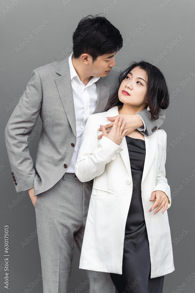 Asian business couple embracing each other in front of the gray background. Asian business couple embracing each other in front of the gray background.