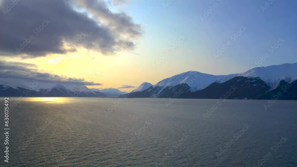 Drone rising up and showing the sun and mountains at sunrise along the Seward Highway. 4k drone.