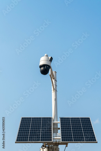 Solar powered surveillance camera. Solar panels powering a surveillance camera in a city park