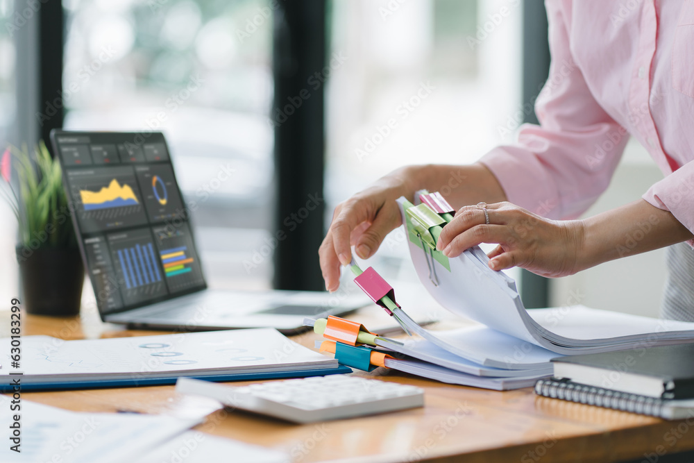 A businesswoman is sifting through stacks of paper files and folders