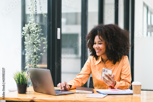 African American businesswoman or accountant with afro hair using a calculator, graphs, and charts to analyze market data, balance sheets, accounts, and net profits.