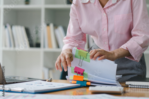 Schilderij op canvas A businesswoman is sifting through stacks of paper files and folders that contain both incomplete and completed documents