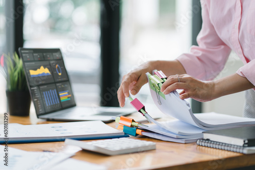 A businesswoman is sifting through stacks of paper files and folders that contain both incomplete and completed documents. Selective focus photo