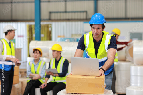 Architect or engineering man or worker standing and checking large warehouse with computer. Caucasian business manager standing and working with warehouse building background.
