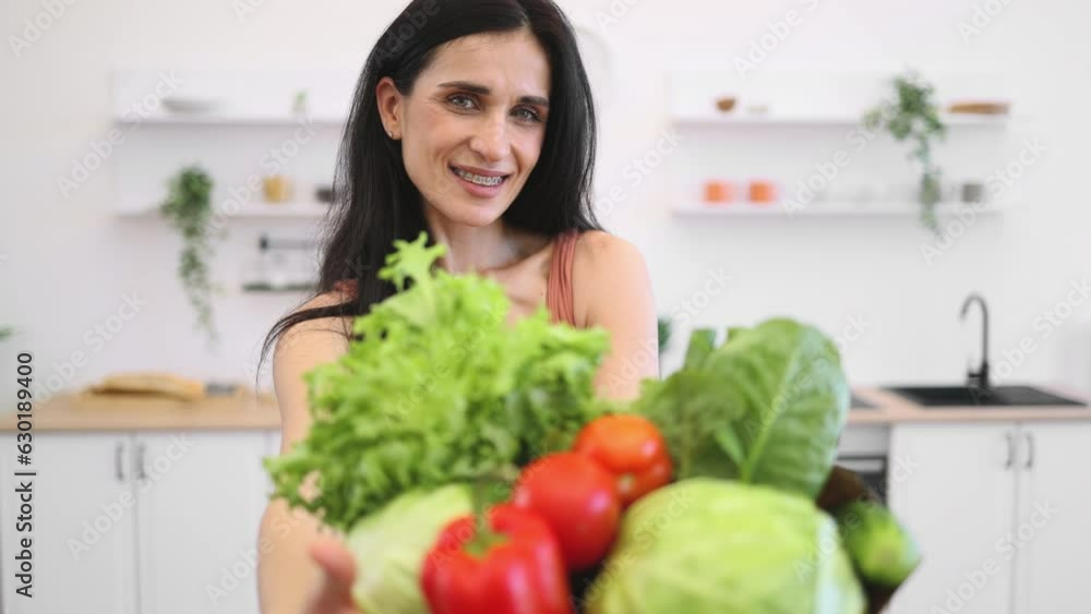 Portrait of beautiful fit lady in sports clothes posing with shopping bag full of greens and fresh vegetables at home. Adult athlete controlling weight with regular exercising and healthy eating. Portrait of beautiful fit lady in sports clothes posing with shopping bag full of greens and fresh vegetables at home. Adult athlete controlling weight with regular exercising and healthy eating.