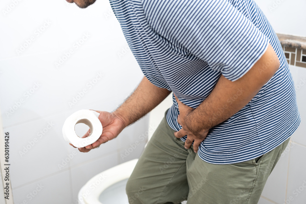 Male suffers from diarrhea holds toilet paper roll in front toilet bowl