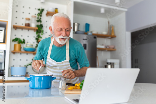 Obraz na plátne Happy senior man having fun cooking at home - Elderly person preparing health lu