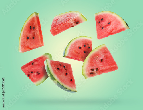 Slices of fresh juicy watermelon falling on turquoise background