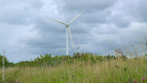 Wind turbine with stormy sky and low grassy approach. Half speed slow motion. photo