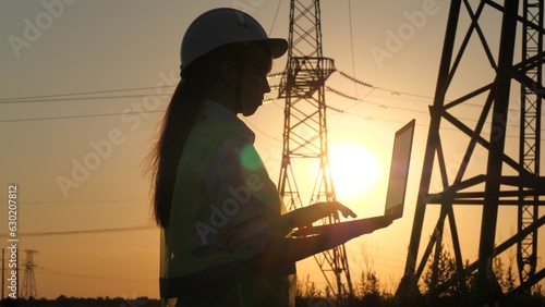 silhouette electrical engineer, work laptop sunset, electric tower, digital hand, engineer hardhat, industry concept, data checks, work concept, high voltage, studying engineer with electric towers