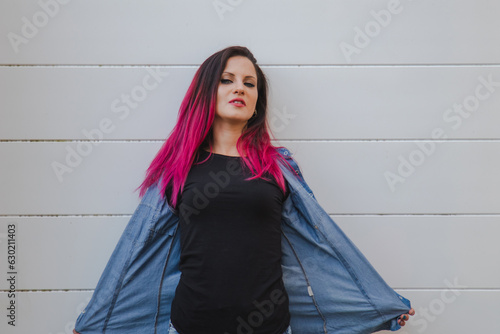 urban red haired woman posing in denim clothes on the wall