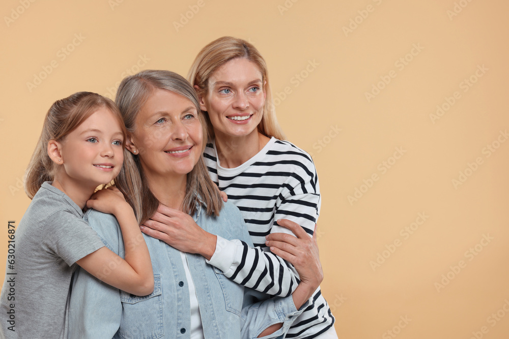 Three generations. Happy grandmother, her daughter and granddaughter on beige background, space for text Three generations. Happy grandmother, her daughter and granddaughter on beige background, space for text