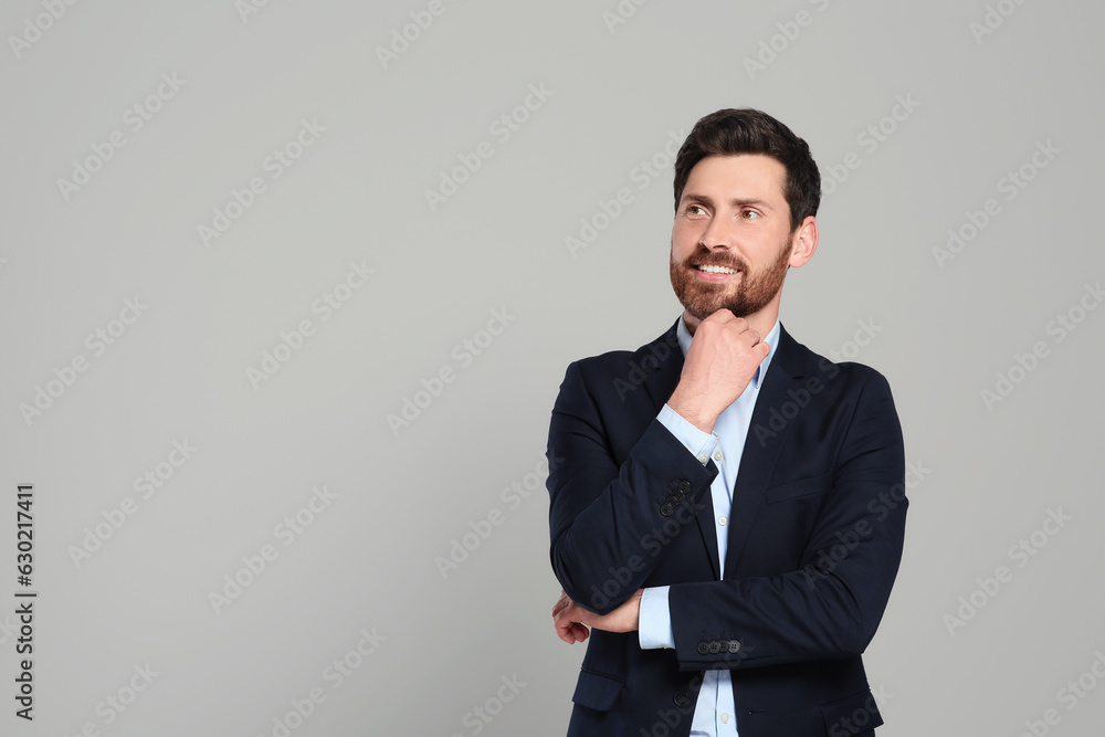 Handsome real estate agent in nice suit on grey background, space for text Handsome real estate agent in nice suit on grey background, space for text