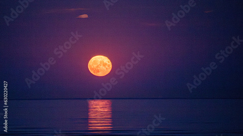 Canvas Print Super moon full moon rising above Irish Sea with reflection