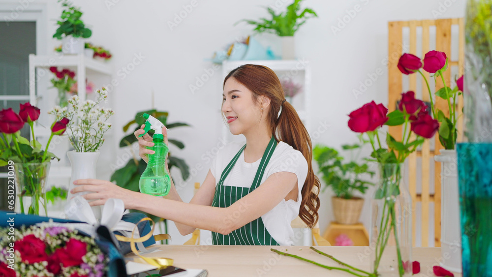 Beautiful asian woman florist spray water on flowers in flower shop add moisture and vitality to the flowers and to prevent flower from wilting in a flower shop. Florist concept, Small business owner Beautiful asian woman florist spray water on flowers in flower shop add moisture and vitality to the flowers and to prevent flower from wilting in a flower shop. Florist concept, Small business owner