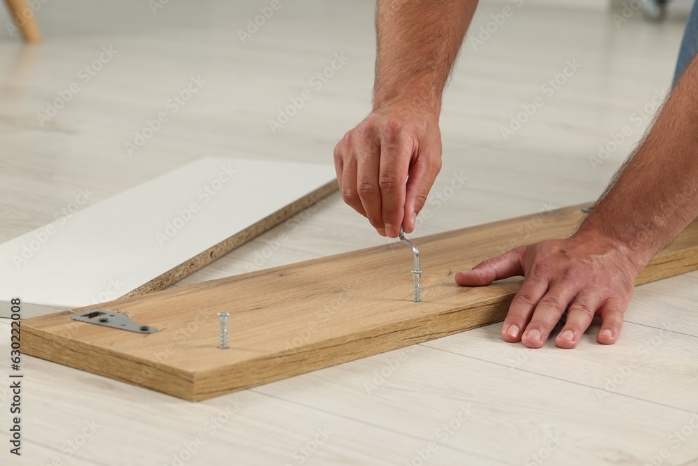 Man with hex key assembling furniture on floor indoors, closeup Man with hex key assembling furniture on floor indoors, closeup