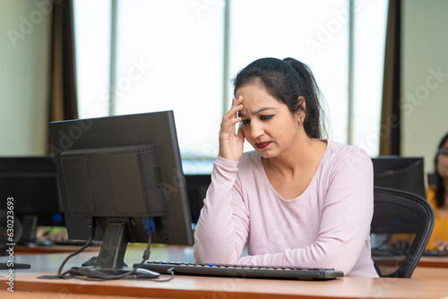 Indian woman in stress while working on computer at office.