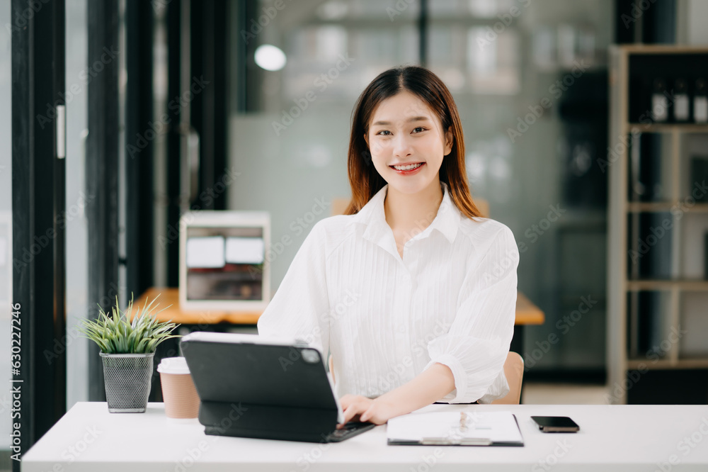 Successful Asian Businesswoman Analyzing Finance on Tablet and Laptop at modern Office Desk tax, report, accounting, statistics, and analytical research concept. Successful Asian Businesswoman Analyzing Finance on Tablet and Laptop at modern Office Desk tax, report, accounting, statistics, and analytical research concept.