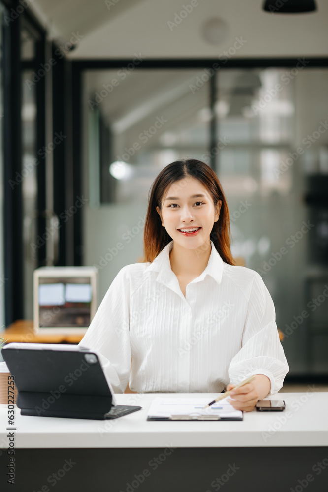 Obraz premium Successful Asian Businesswoman Analyzing Finance on Tablet and Laptop at modern Office Desk tax, report, accounting, statistics, and analytical research concept.
