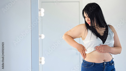 Photos Chubby woman in t-shirt feeling insecure in own body touches fat folds on belly
