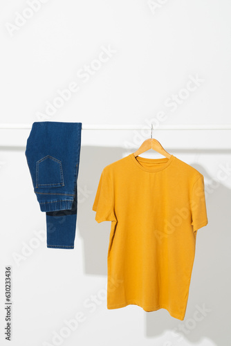 Yellow t shirt and denim trousers on clothes rail with copy space on white background